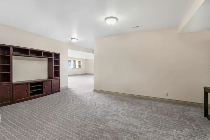 Spacious room with patterned carpet flooring, recessed lighting, and a built-in media center