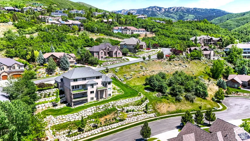 Residential community featuring multiple homes set on a hillside with surrounding mountain terrain