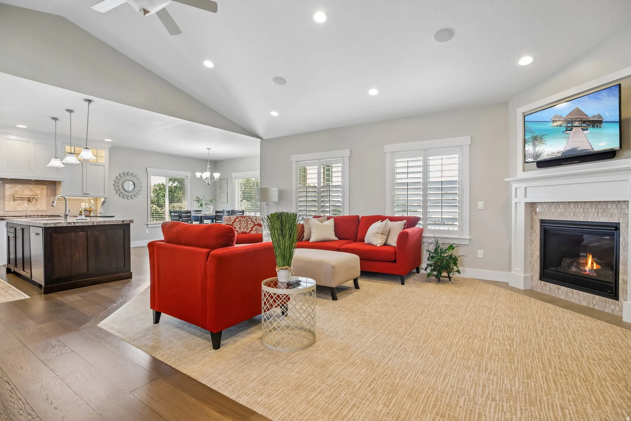 Spacious open-concept living area featuring a vaulted ceiling and recessed lighting, plantation shutters and gas fireplace