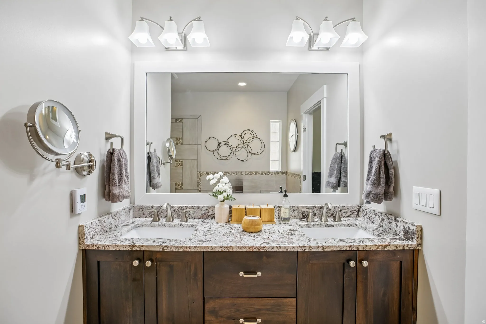 En suite dual basin vanity with a granite countertop, undermount sinks, and brushed nickel fixtures
