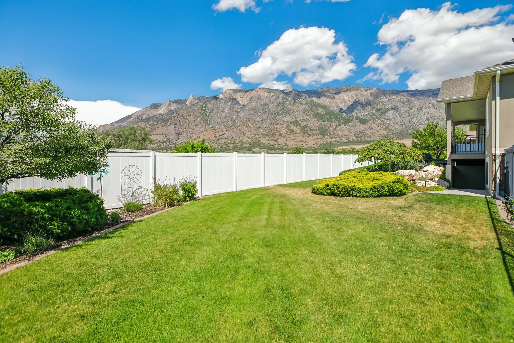 Expansive green lawn with a full white privacy fence