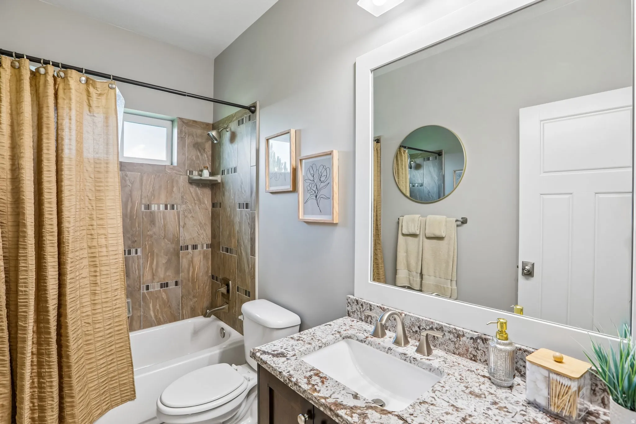 Bathroom featuring a vanity with a white framed mirror, a rectangular undermount sink, and a speckled granite countertop and custom tile surround shower/tub