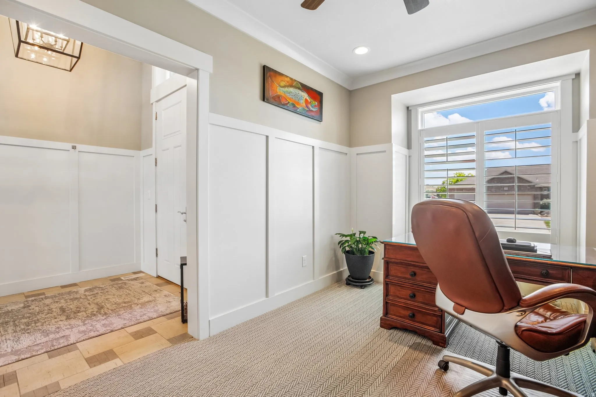 Room featuring board and batten wall paneling, a large window with plantation shutters, recessed lighting, and crown molding