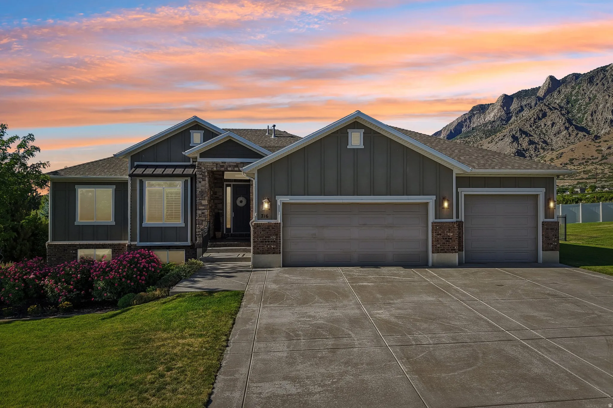 Contemporary single-story home featuring a large covered front porch, a combination of horizontal and vertical cement board, brick and stone accents, wrought iron front fencing and large three car garage, extra height, extra length, with workbench and mez