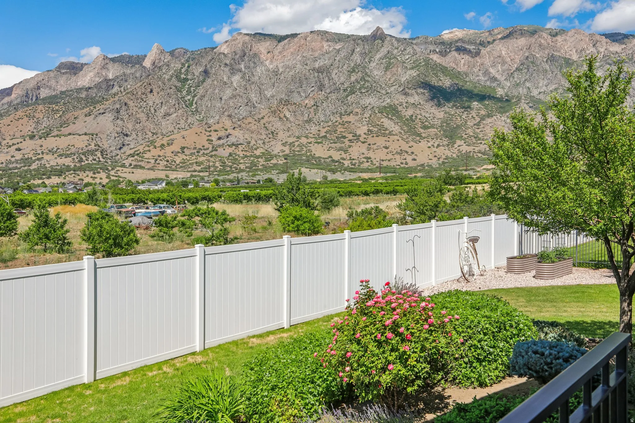 Expansive grounds featuring, mature trees, manicured lawn, and planted garden beds, all set against a stunning mountain views