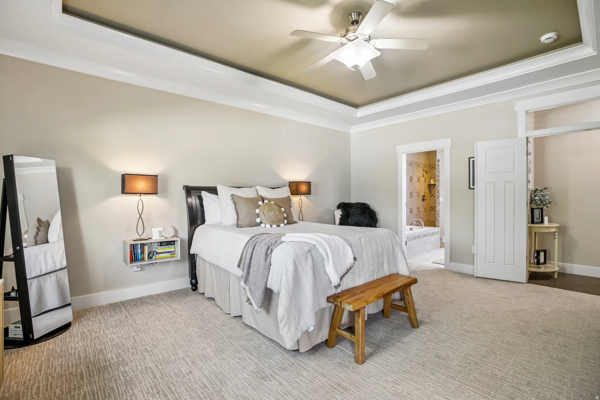 Private main bedroom featuring a tray ceiling with a ceiling fan, light-colored walls, and new patterned carpet