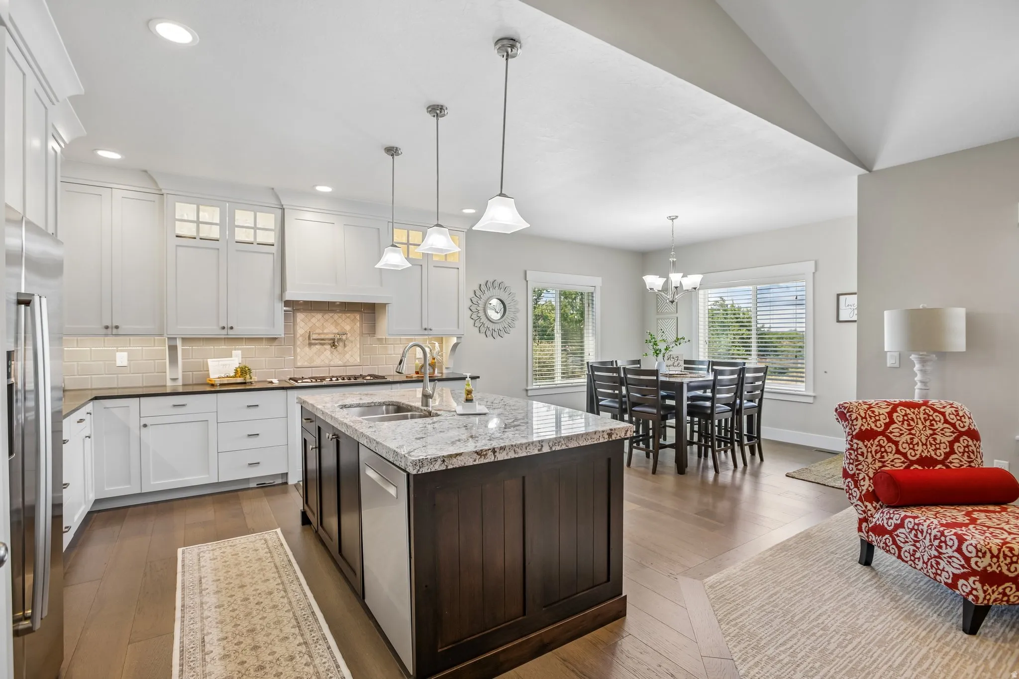 Spacious kitchen featuring a dark wood-finish island with integrated sink, dark-toned perimeter cabinetry, and wood-finish flooring