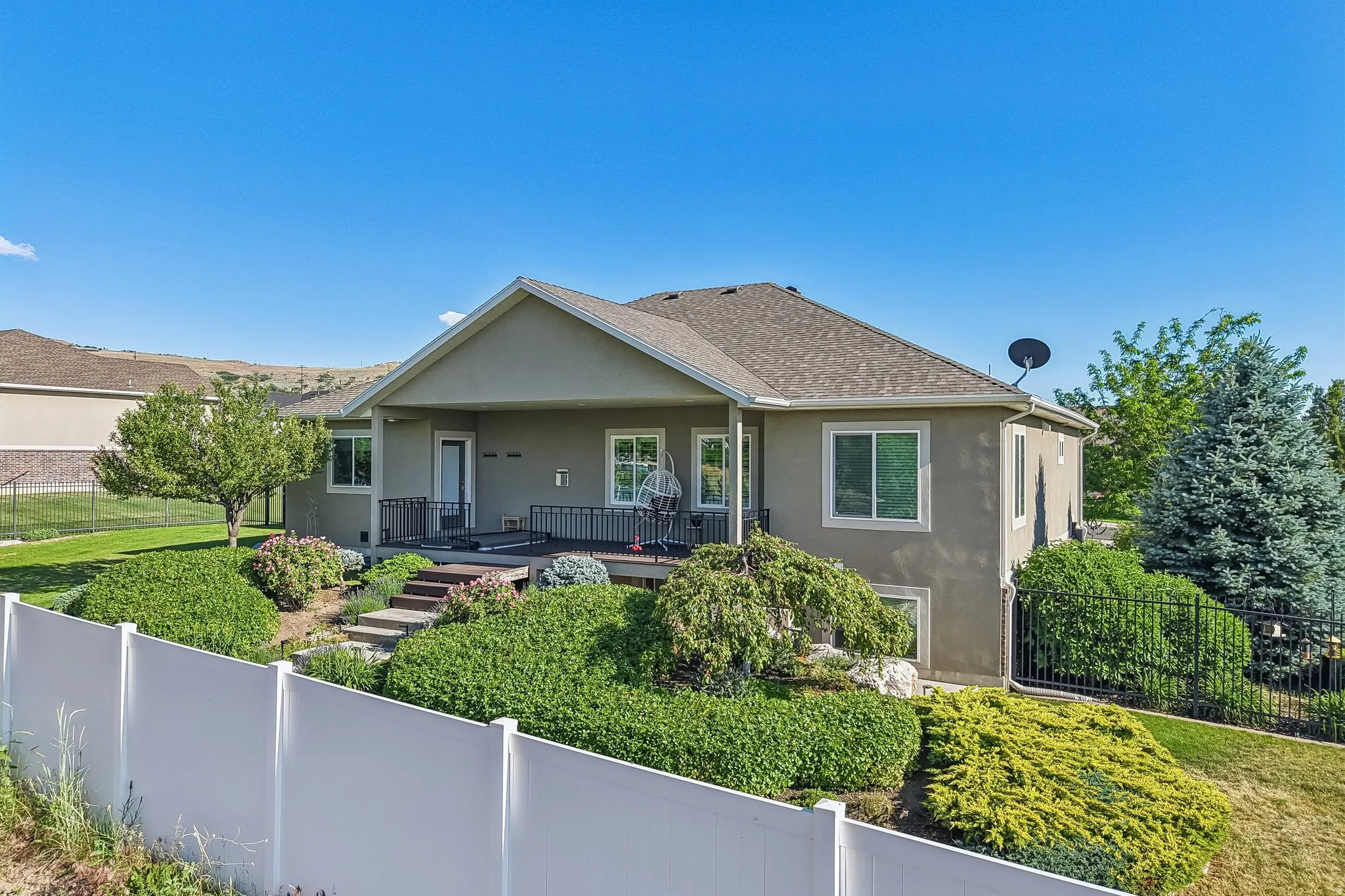 Terraced backyard featuring a covered patio, composite decking, and mature landscaping