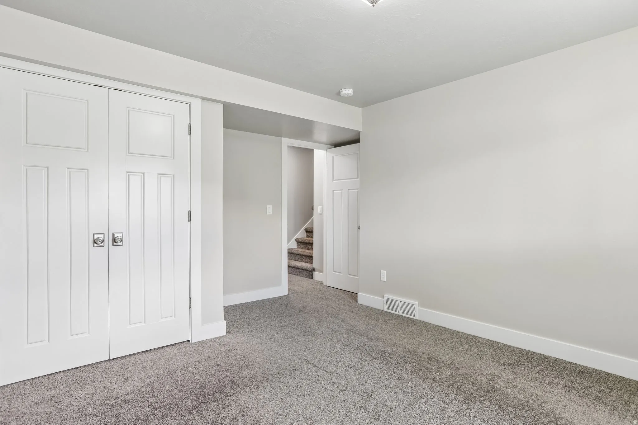 Bedroom 3 - Carpeted room featuring white bi-fold closet doors with square silver hardware, crisp white baseboards, and new cellular shade and fresh paint