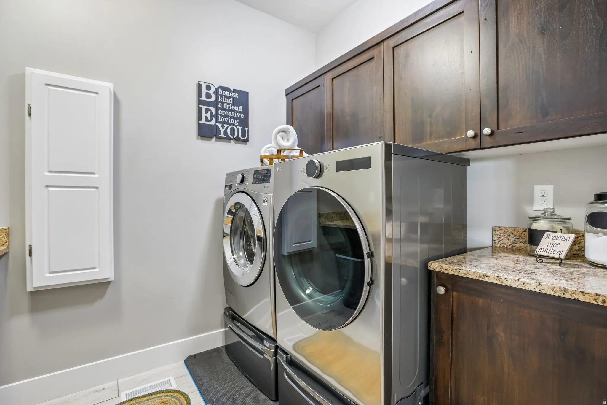 Dedicated laundry space featuring dark wood-finish cabinetry, a light-toned granite countertop, and light walls, built in ironing board and drying rod