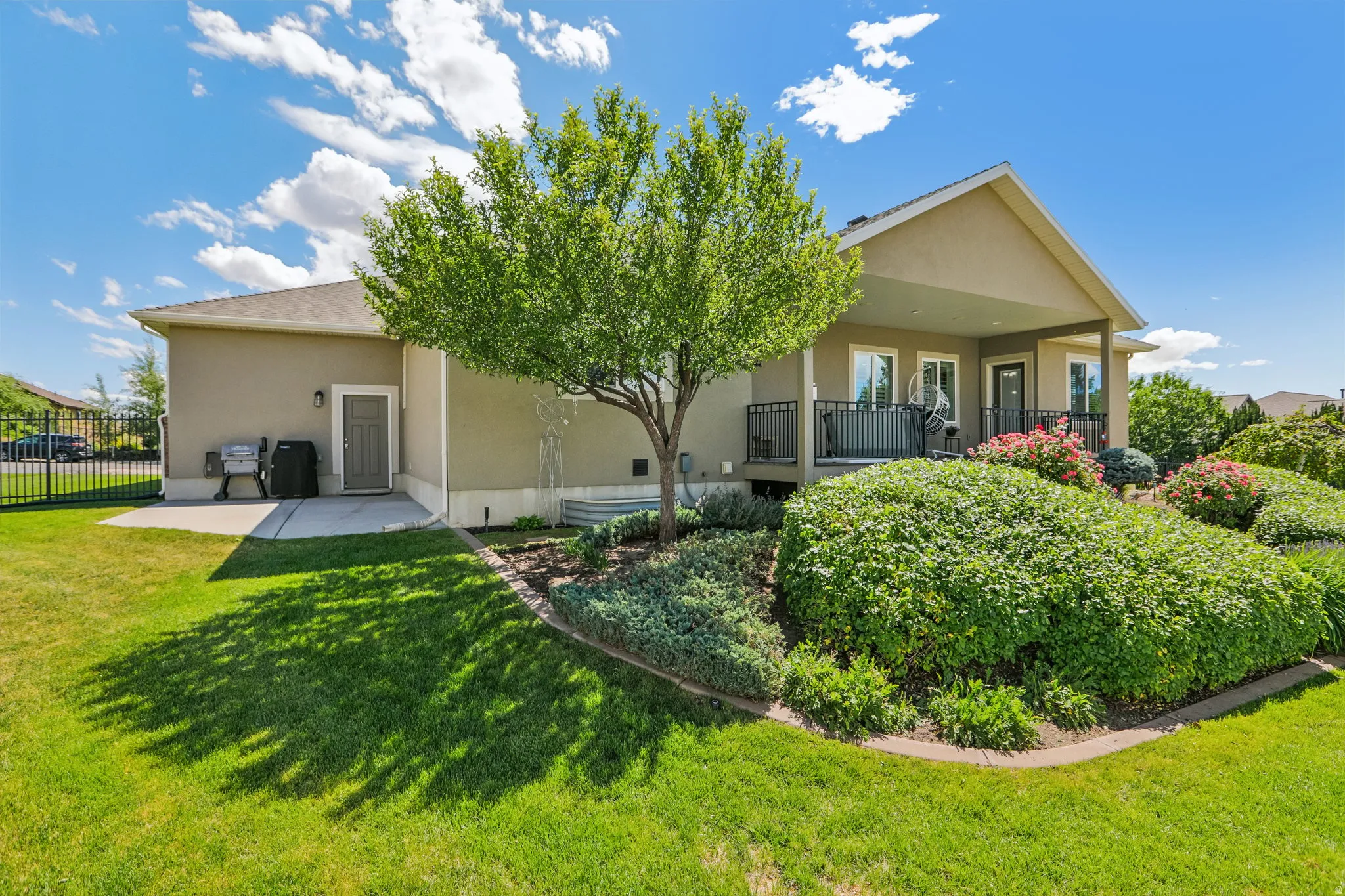 Rear exterior featuring a covered patio with black railing, a walk-out basement door, and a concrete patio