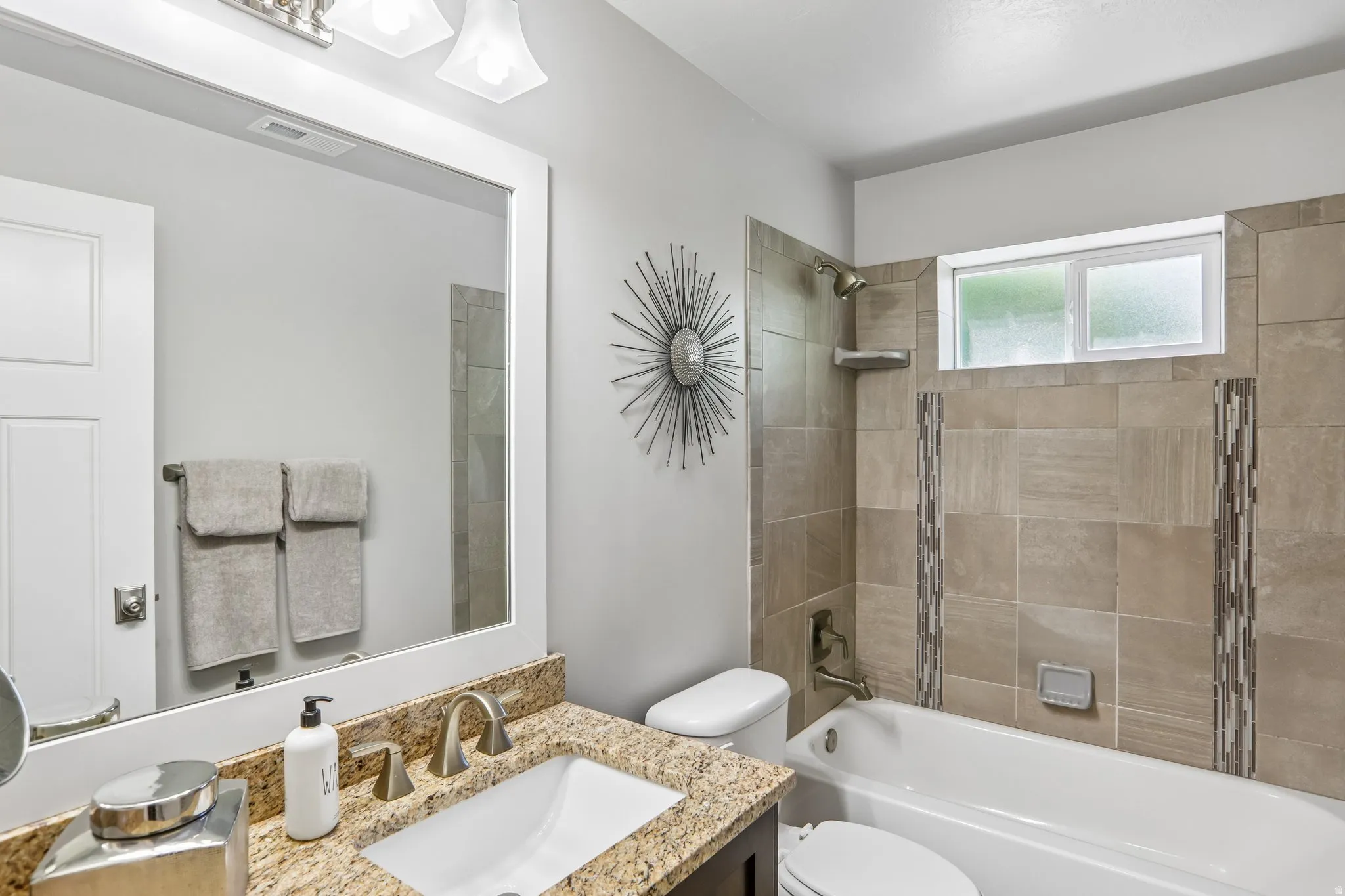 Bathroom featuring a white framed mirror, a vanity with a granite countertop, an undermount sink, and a brushed nickel faucet