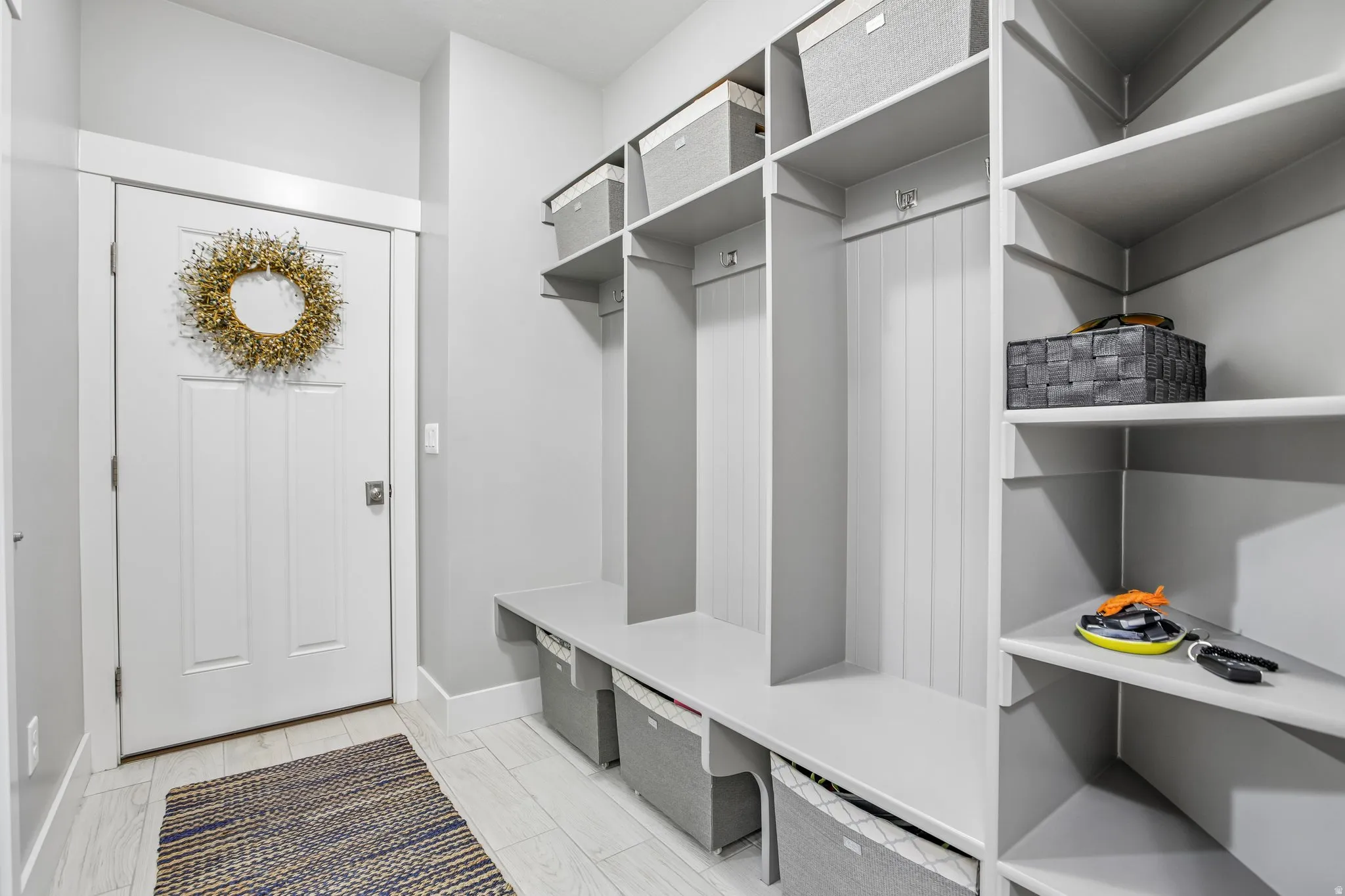 Mudroom featuring built-in gray cabinetry with open shelving and bench seating