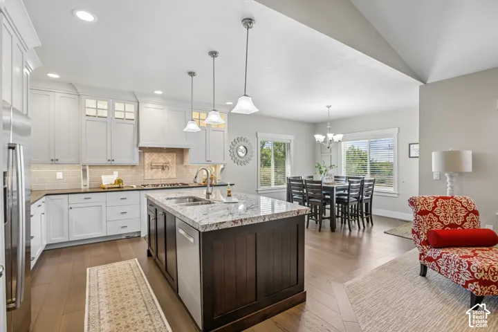 Spacious kitchen featuring a dark wood-finish island with integrated sink, dark-toned perimeter cabinetry, and wood-finish flooring