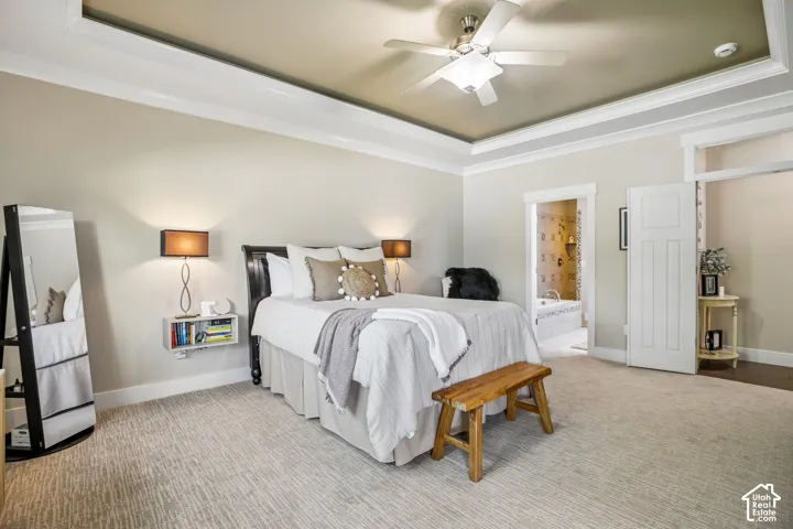Private main bedroom featuring a tray ceiling with a ceiling fan, light-colored walls, and new patterned carpet
