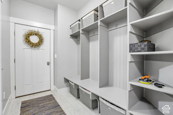 Mudroom featuring built-in gray cabinetry with open shelving and bench seating