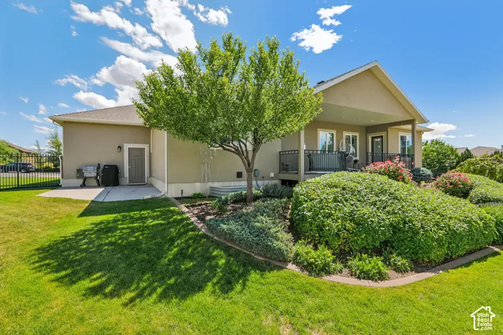 Rear exterior featuring a covered patio with black railing, a walk-out basement door, and a concrete patio