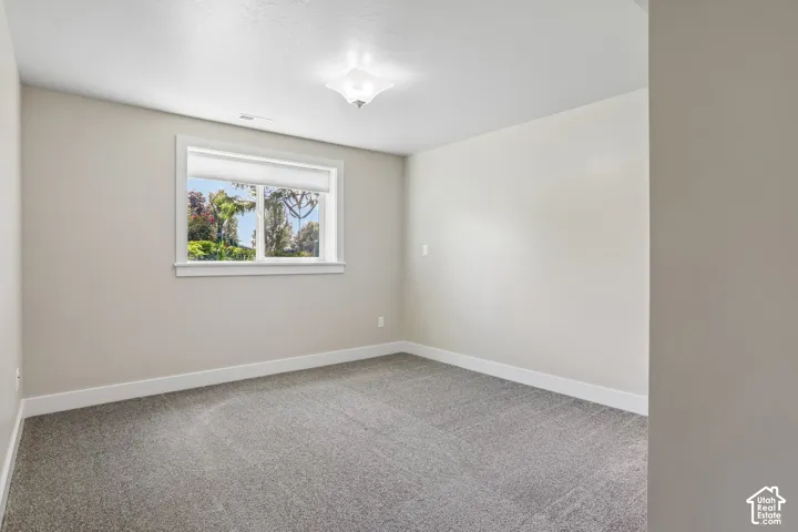 Bedroom 3 - Neutral tone wall paint with white trim, light brown carpet flooring, and a single window with picture frame molding and a new cellular shade