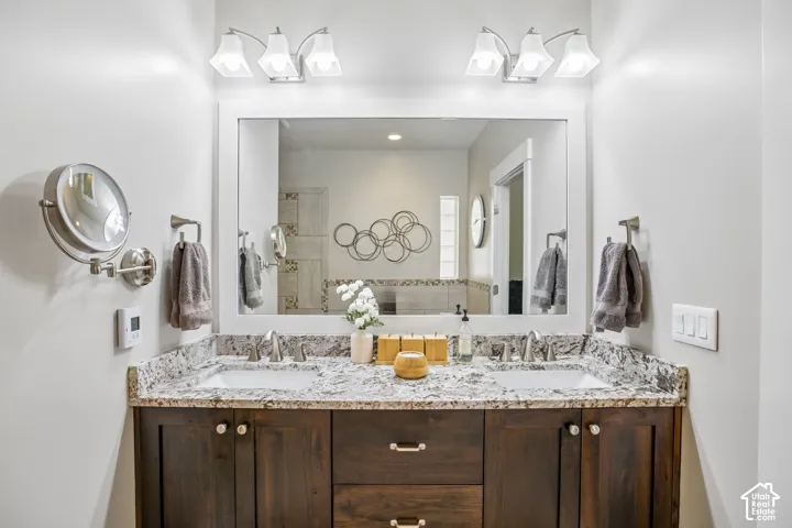 En suite dual basin vanity with a granite countertop, undermount sinks, and brushed nickel fixtures