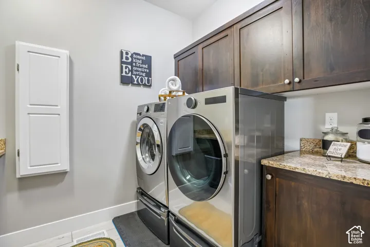 Dedicated laundry space featuring dark wood-finish cabinetry, a light-toned granite countertop, and light walls, built in ironing board and drying rod