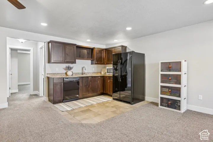 Kitchenette featuring dark wood cabinetry, a stainless steel sink with a high-arc faucet, and granite-style countertops and microwave