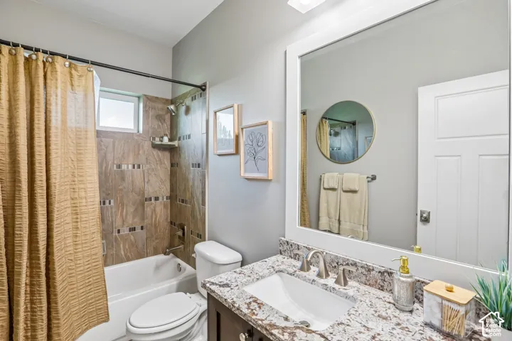 Bathroom featuring a vanity with a white framed mirror, a rectangular undermount sink, and a speckled granite countertop and custom tile surround shower/tub