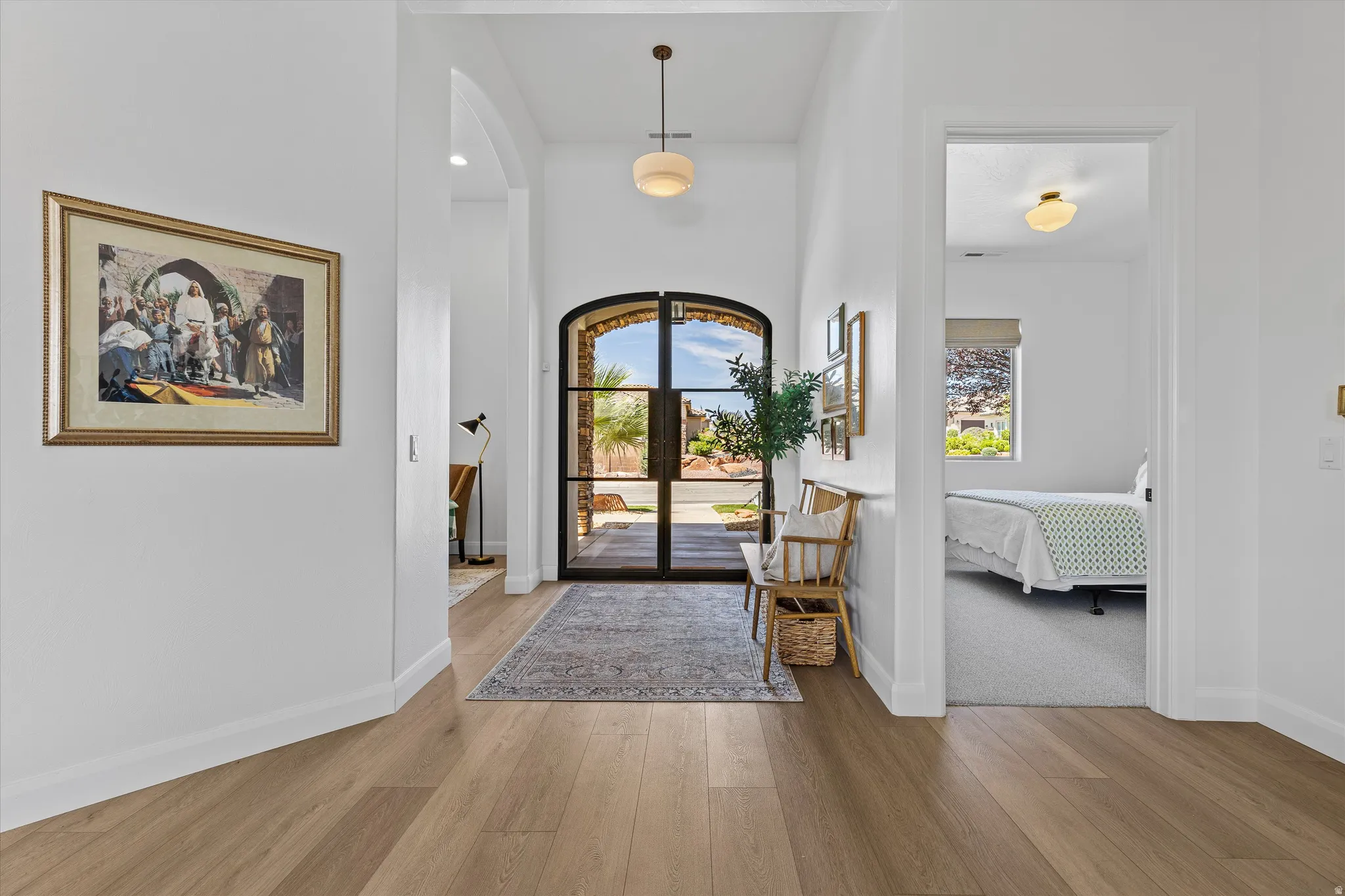 Entryway featuring wood-finish flooring, a contemporary arched doorway with a wrought iron and glass insert, and a geometric pendant light fixture