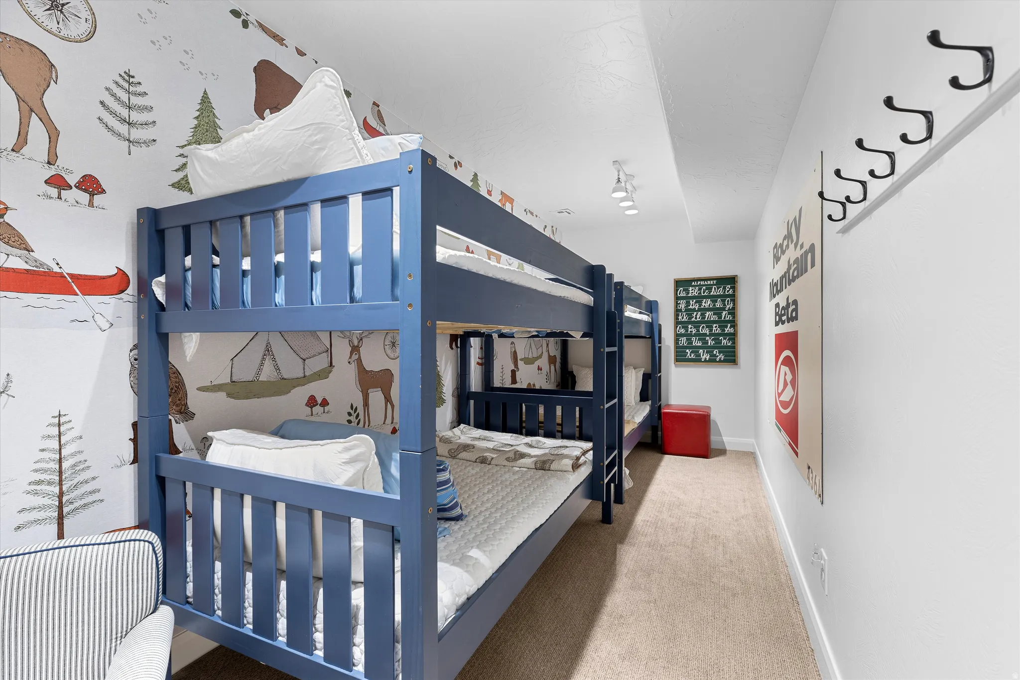 Room featuring bunk beds, patterned accent wall, and track lighting