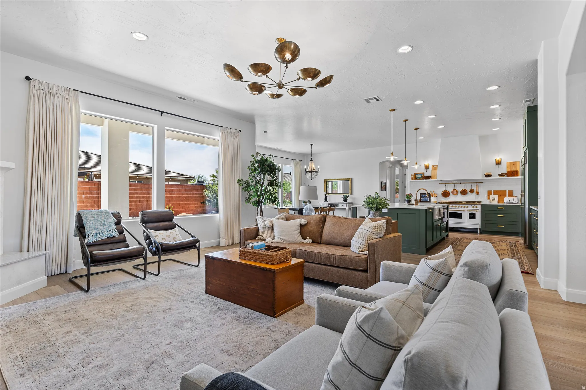Open-concept living area featuring light wood-finish flooring, recessed lighting, and a contemporary chandelier