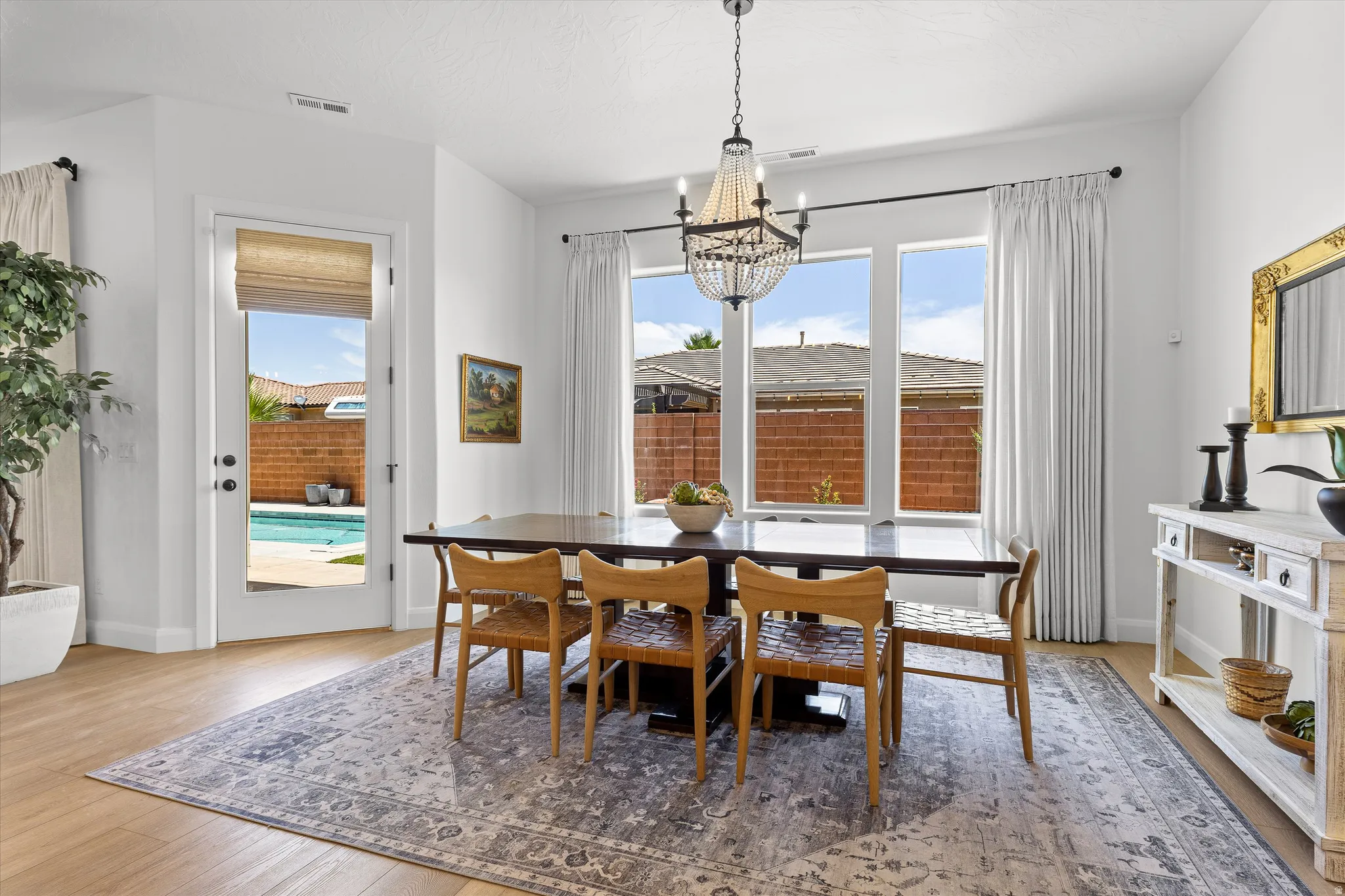 Dining area with wood-finish flooring, a contemporary chandelier, and ample natural light from multiple windows