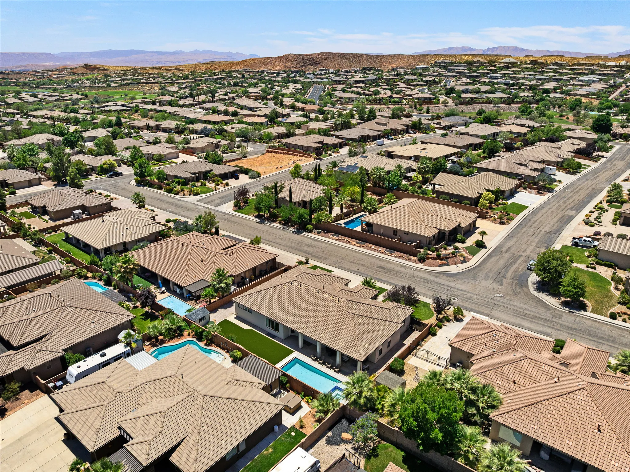 Extensive residential community featuring numerous single-story homes, mature landscaping, paved streets, and a mountainous backdrop