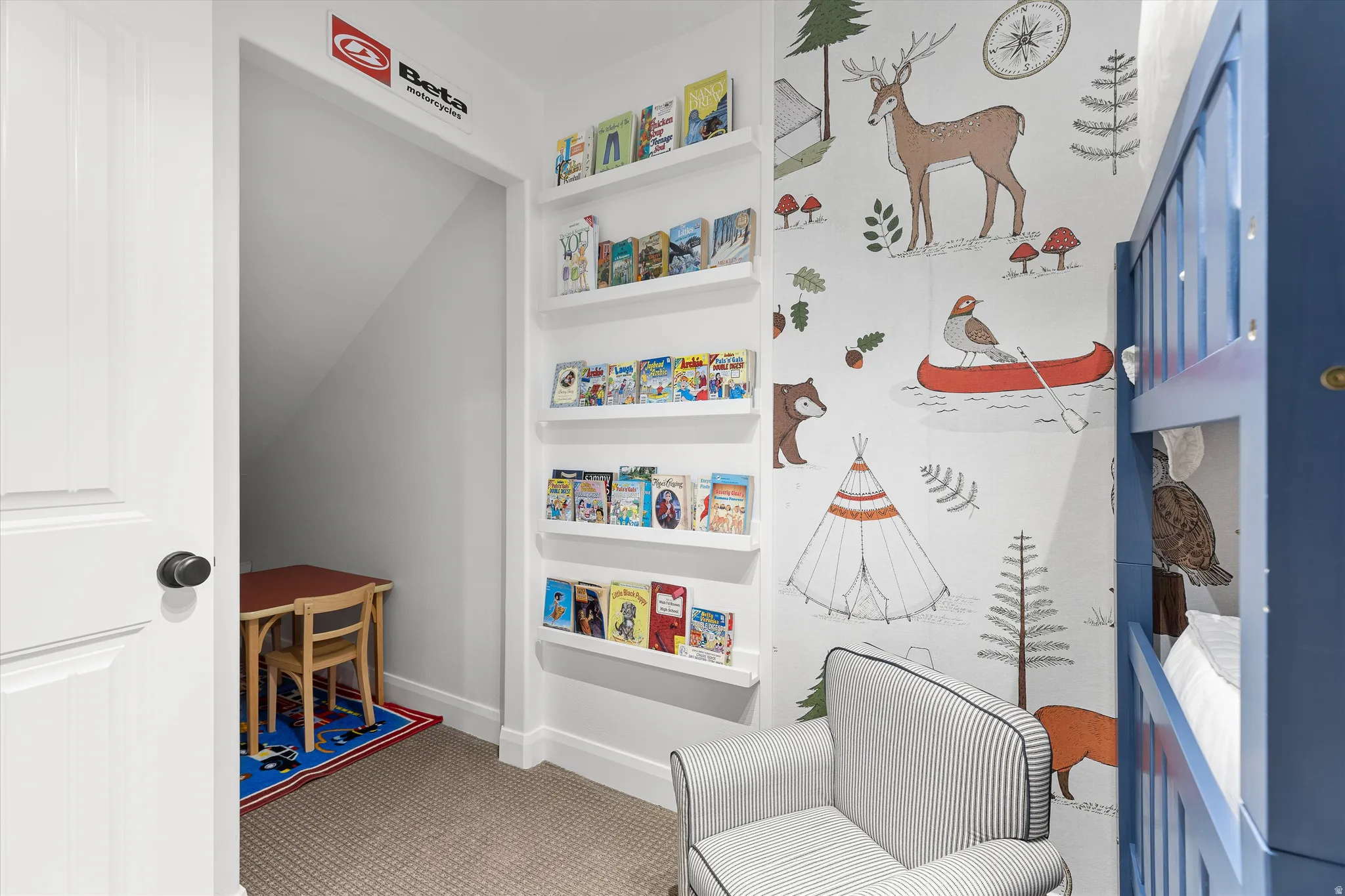 White built-in shelving provides storage within this carpeted room, featuring a decorative wall mural