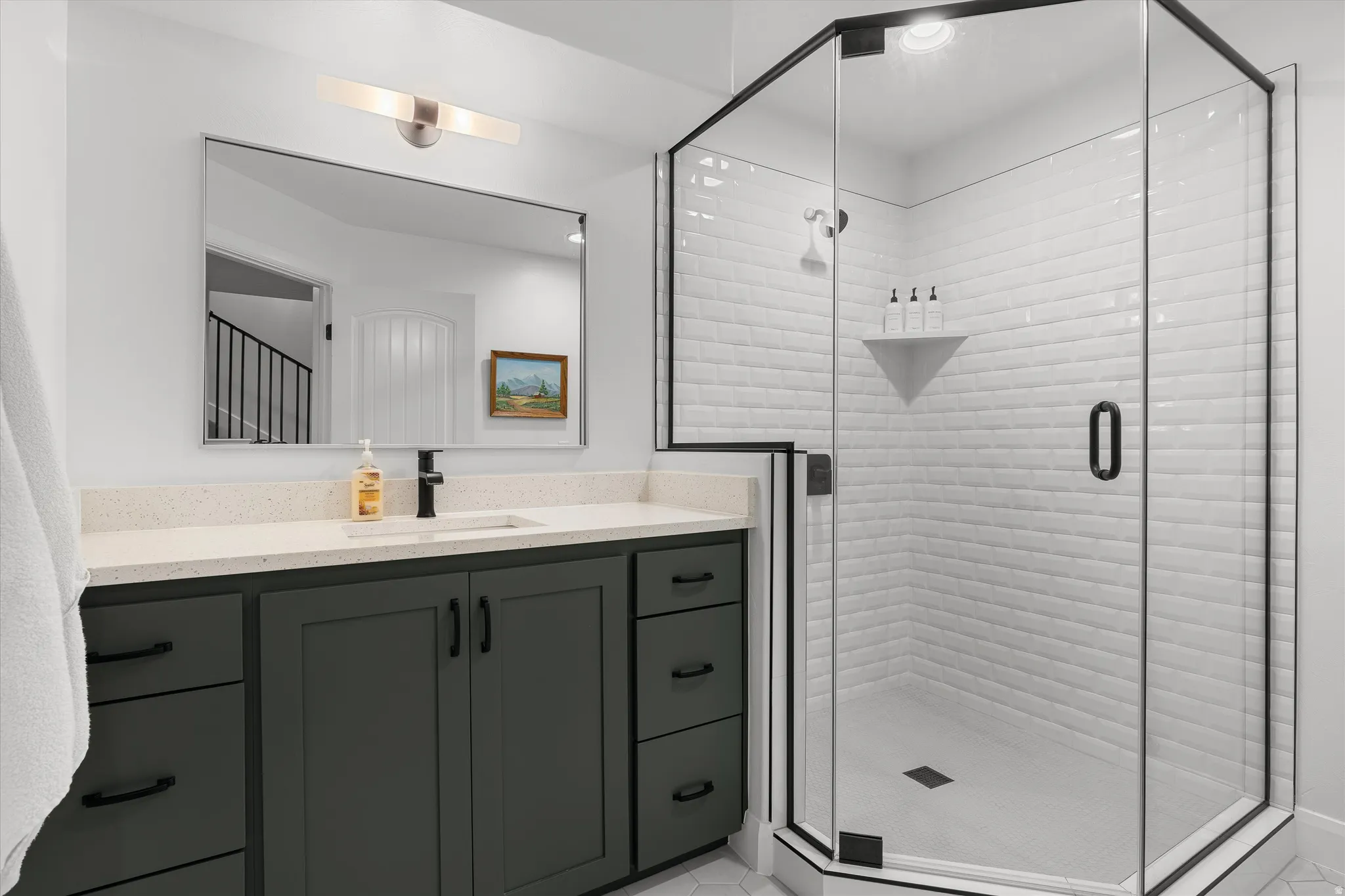 Contemporary bathroom featuring a spacious glass-enclosed shower with white subway tile surround and a built-in corner shelf