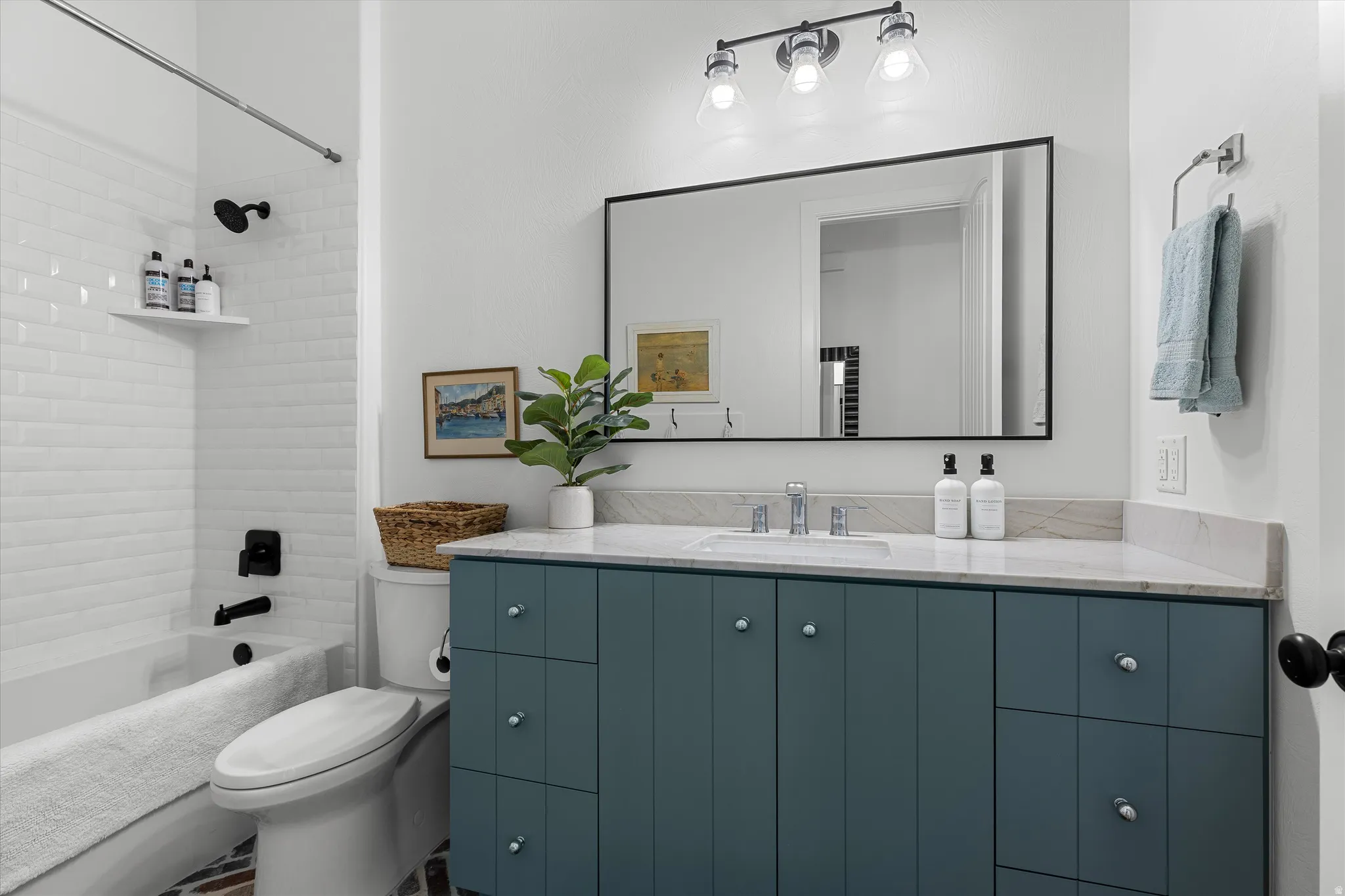 Bathroom with white subway tile shower surround, matte black shower fixtures, a blue vanity with a white countertop, and a large wall-mounted mirror