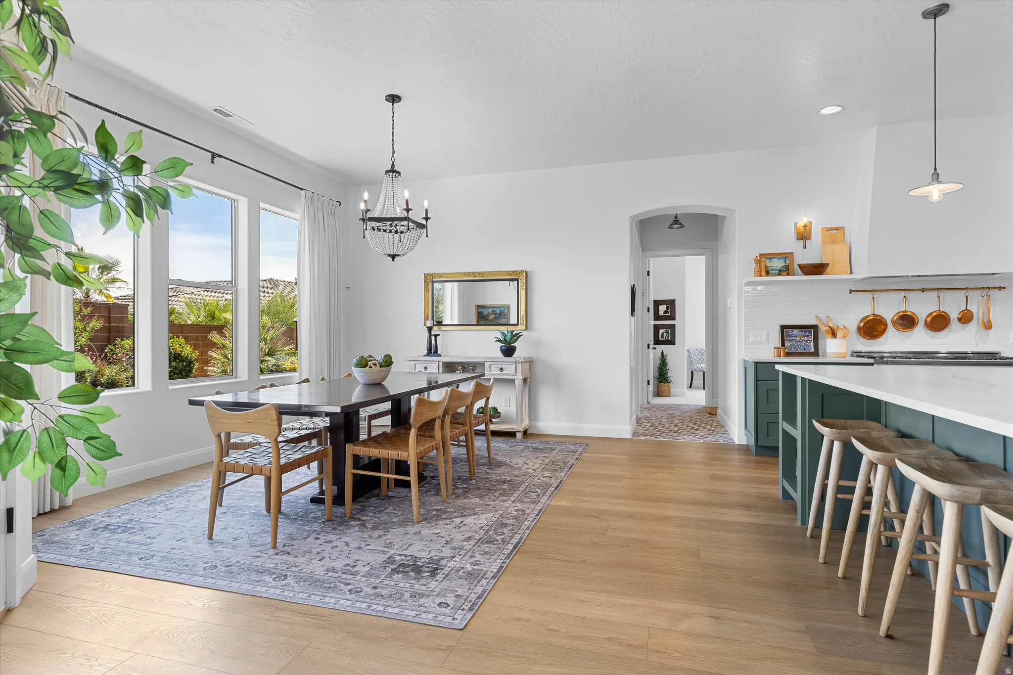 Bright dining area featuring wood-finish flooring, a contemporary chandelier, and an expansive window line