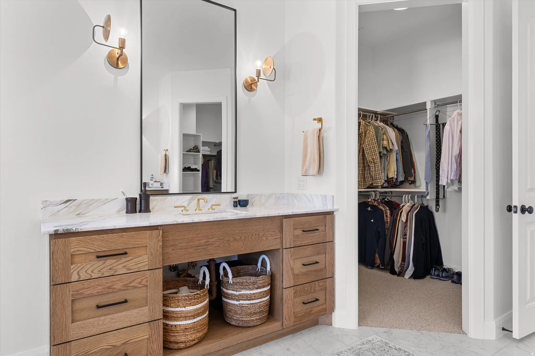 Bathroom vanity featuring a single undermount sink, brass fixtures, and a stone countertop