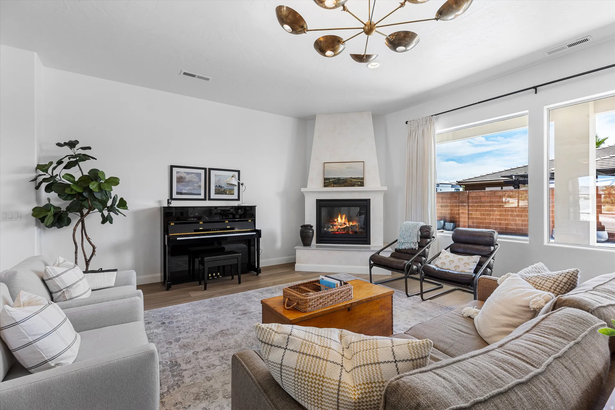 Spacious living area featuring a corner fireplace with a white mantel, large windows, and wood-finish flooring