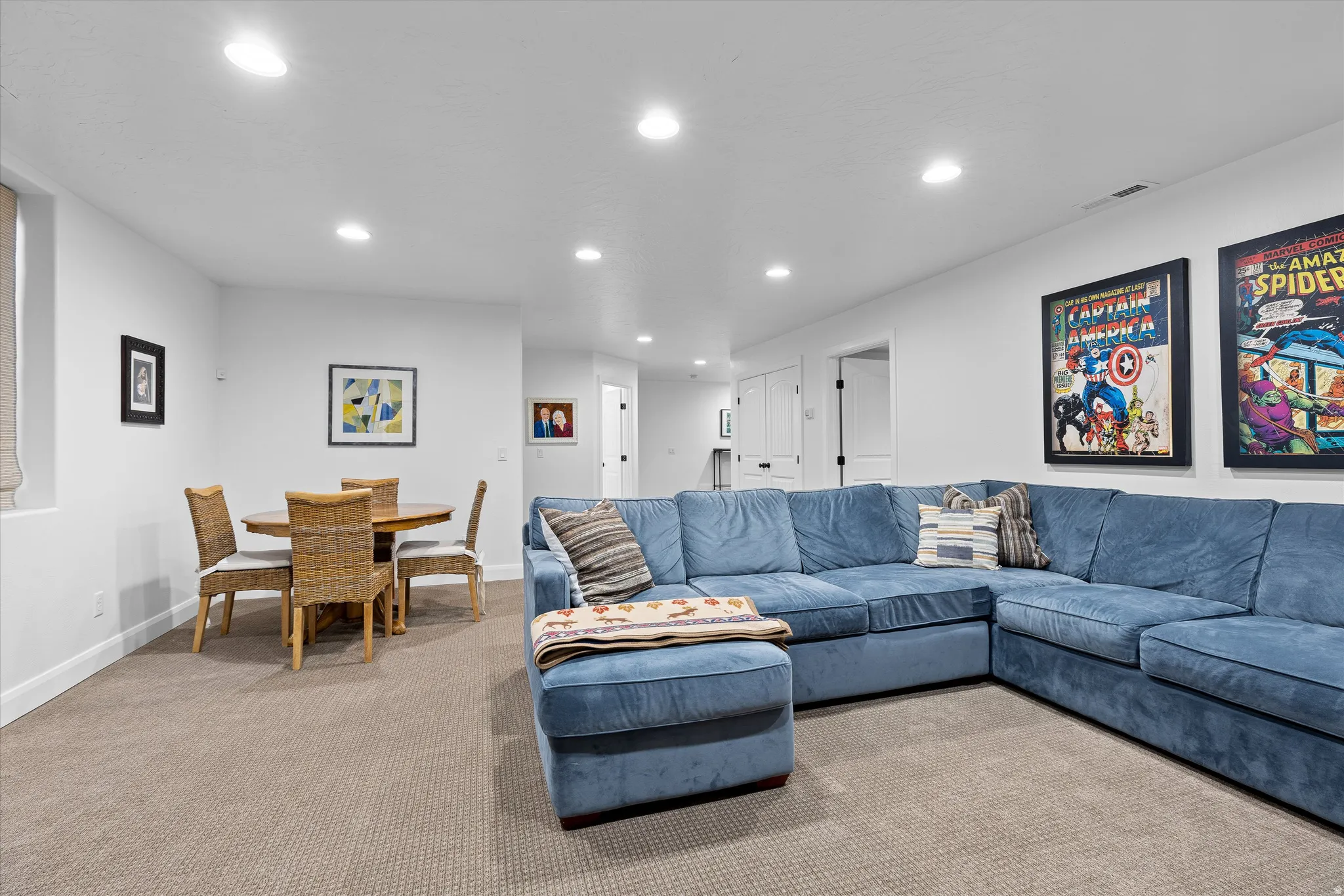 Recessed lighting illuminates this carpeted room, featuring white walls and white trim