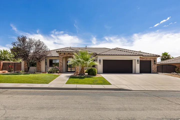 Mediterranean-style residence featuring a tile roof, stucco exterior with stone accents, a multi-car garage, and a concrete driveway