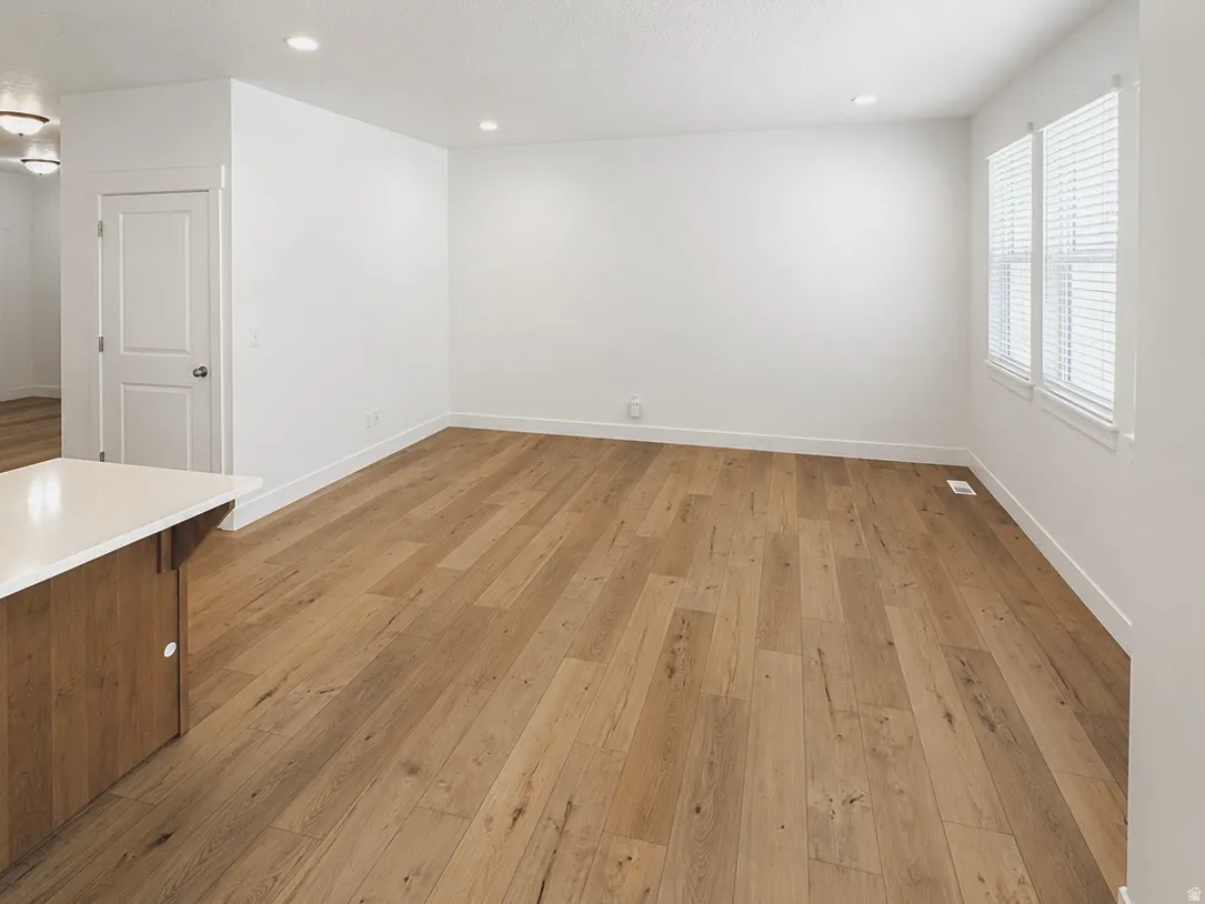 Open-concept living area featuring wood-finish flooring, recessed lighting, and bright white walls