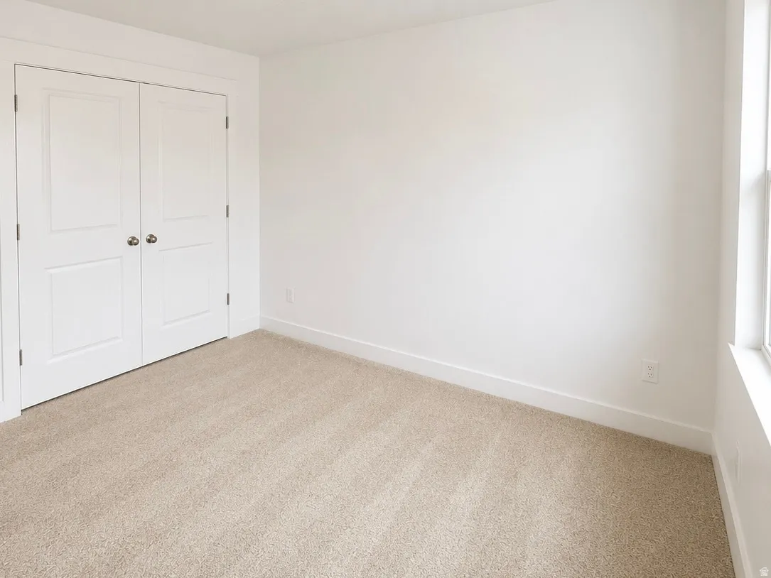 Neutral-toned carpeted interior space featuring white walls and trim