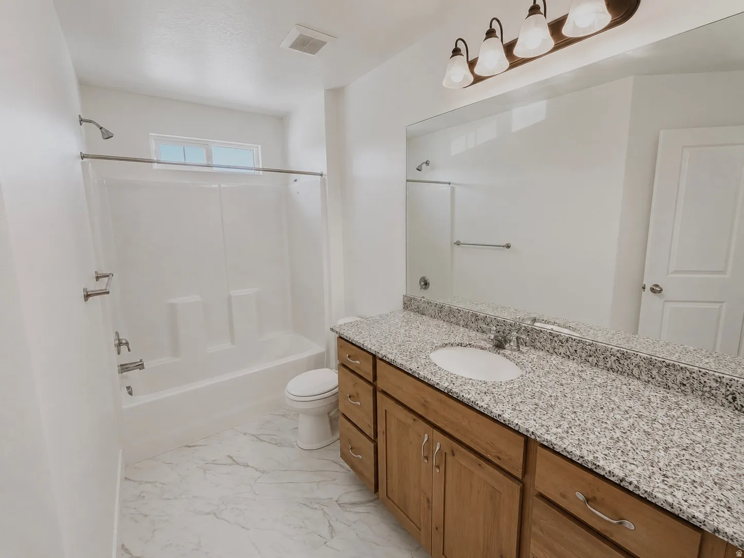 Bathroom featuring a wood-finish vanity with a granite-style countertop and an integrated single-basin sink