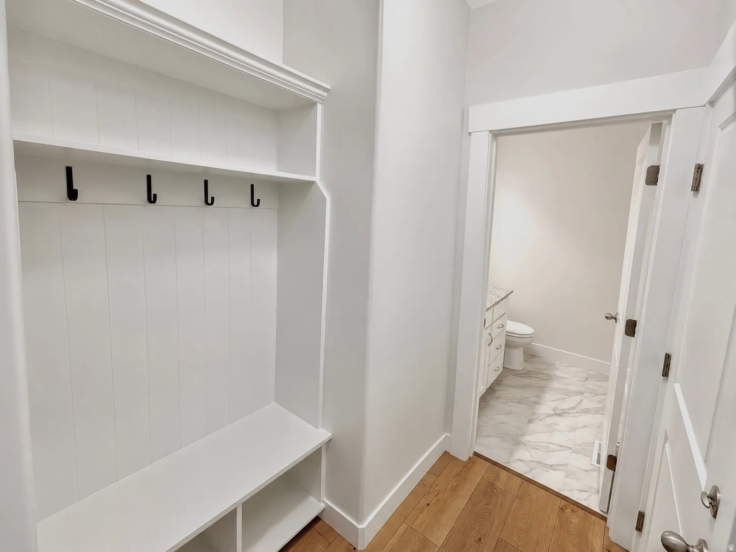 Built-in white mudroom bench and storage unit with black hooks