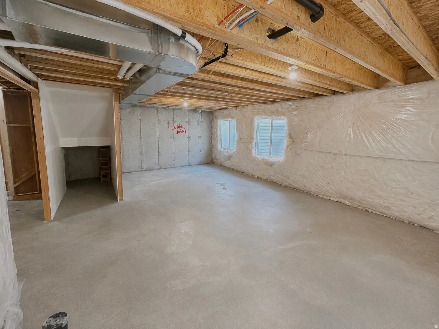 Unfinished basement with exposed wood joists, concrete flooring, and visible ductwork