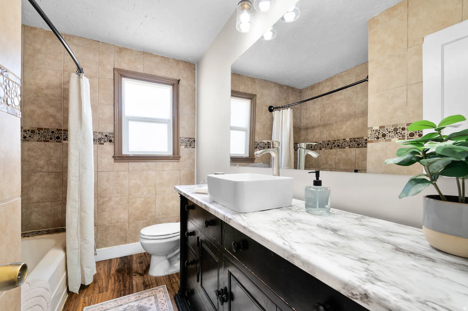 Bathroom featuring a dark wood-finish vanity with a light-toned countertop, a vessel sink, and a large wall-mounted mirror