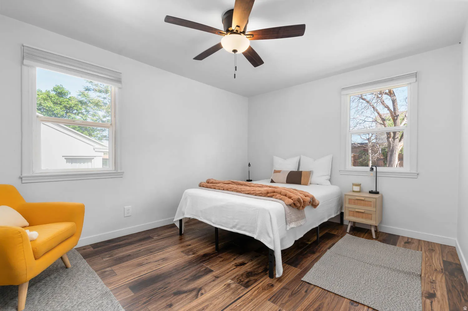 Interior room featuring wood-finish flooring, white walls, and two large windows