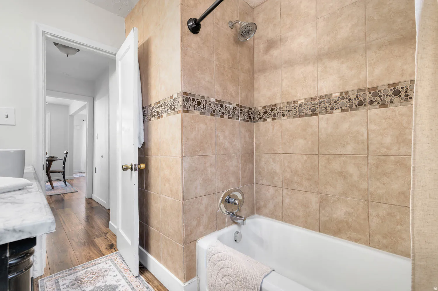 Bathtub with ceramic tile surround, mosaic accent band, and chrome fixtures