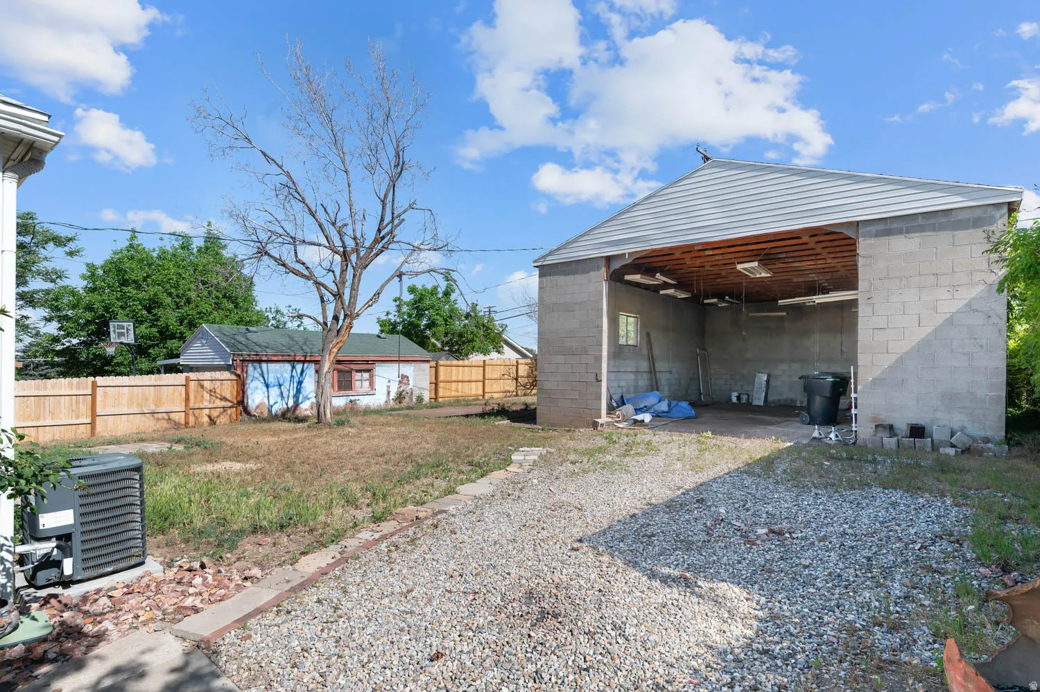 Large cinder block outbuilding featuring a metal roof and open bay