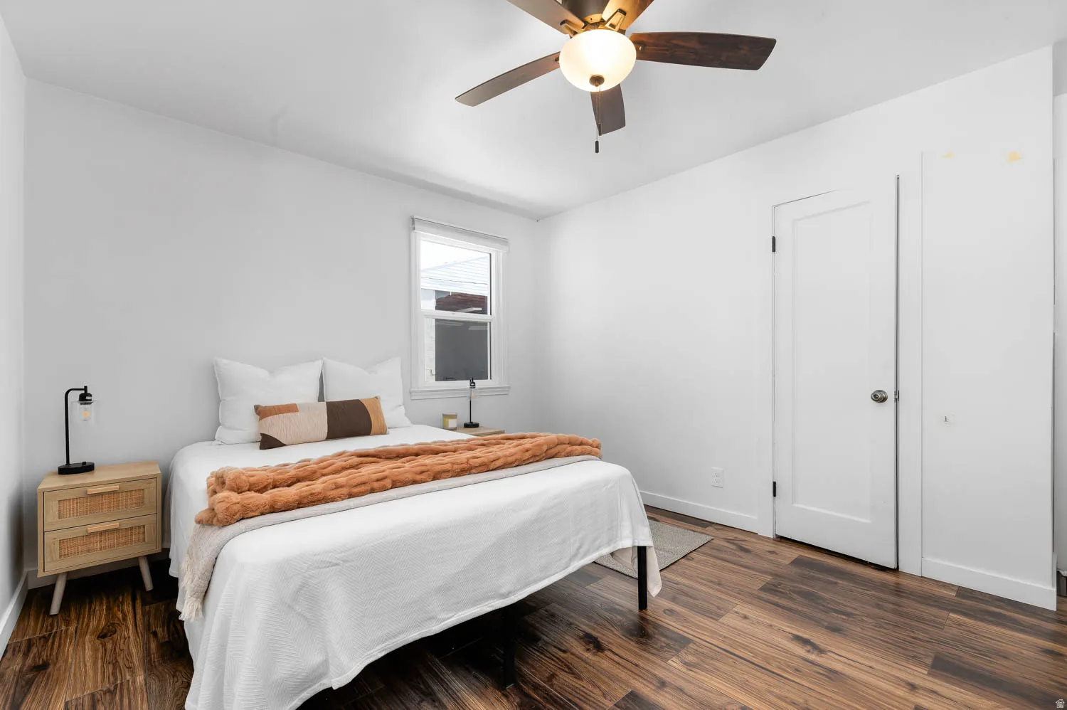 Bedroom featuring wood-finish flooring, a ceiling fan with integrated lighting, a single window, and a white interior door