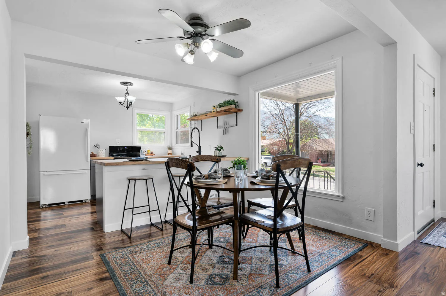 Dining area featuring wood-finish flooring, a ceiling fan with integrated lighting, and a large window